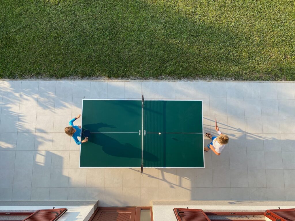 two people playing ping pong on a garden